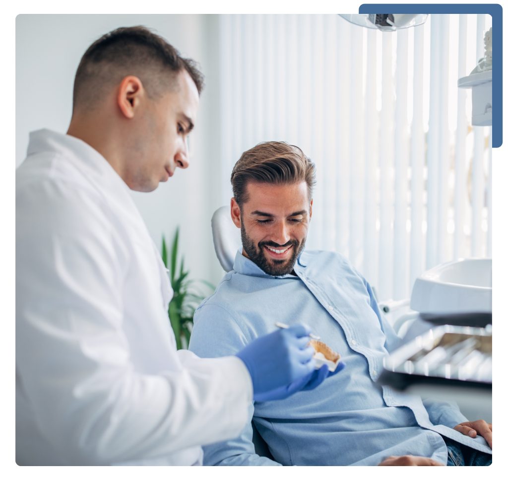 A man seated in a chair while doctor in a white coat stands beside him, likely assisting with health care.
