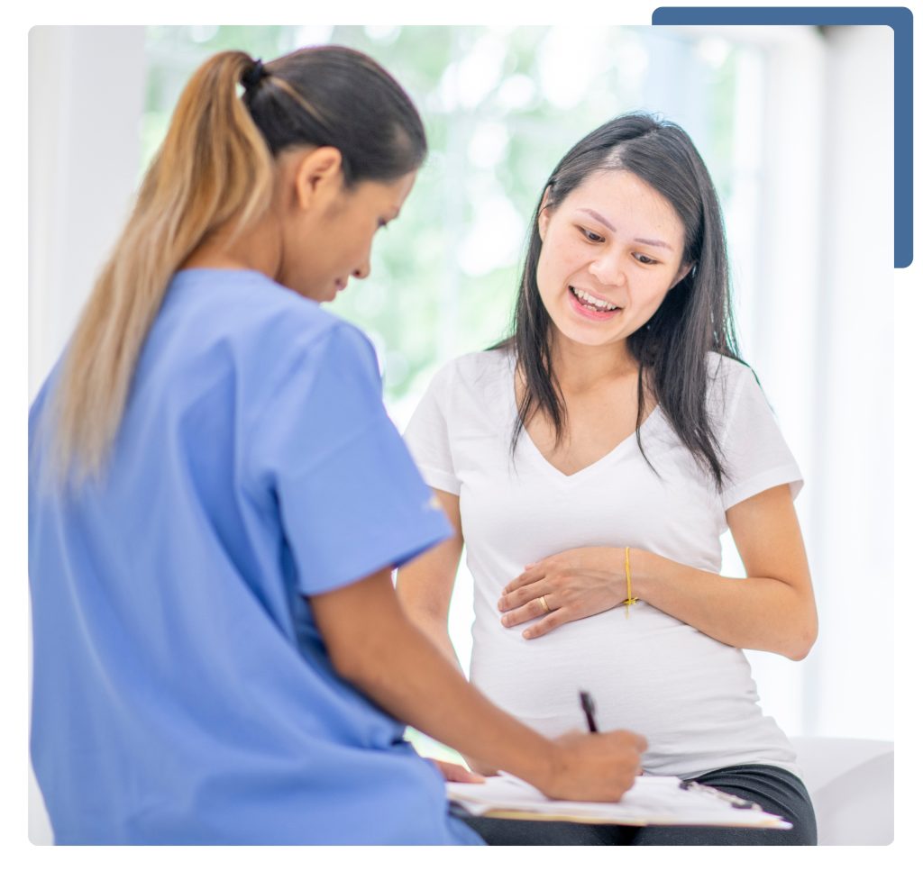 A doctor engages in conversation with a pregnant woman, while another woman holds a clipboard, ready to assist.