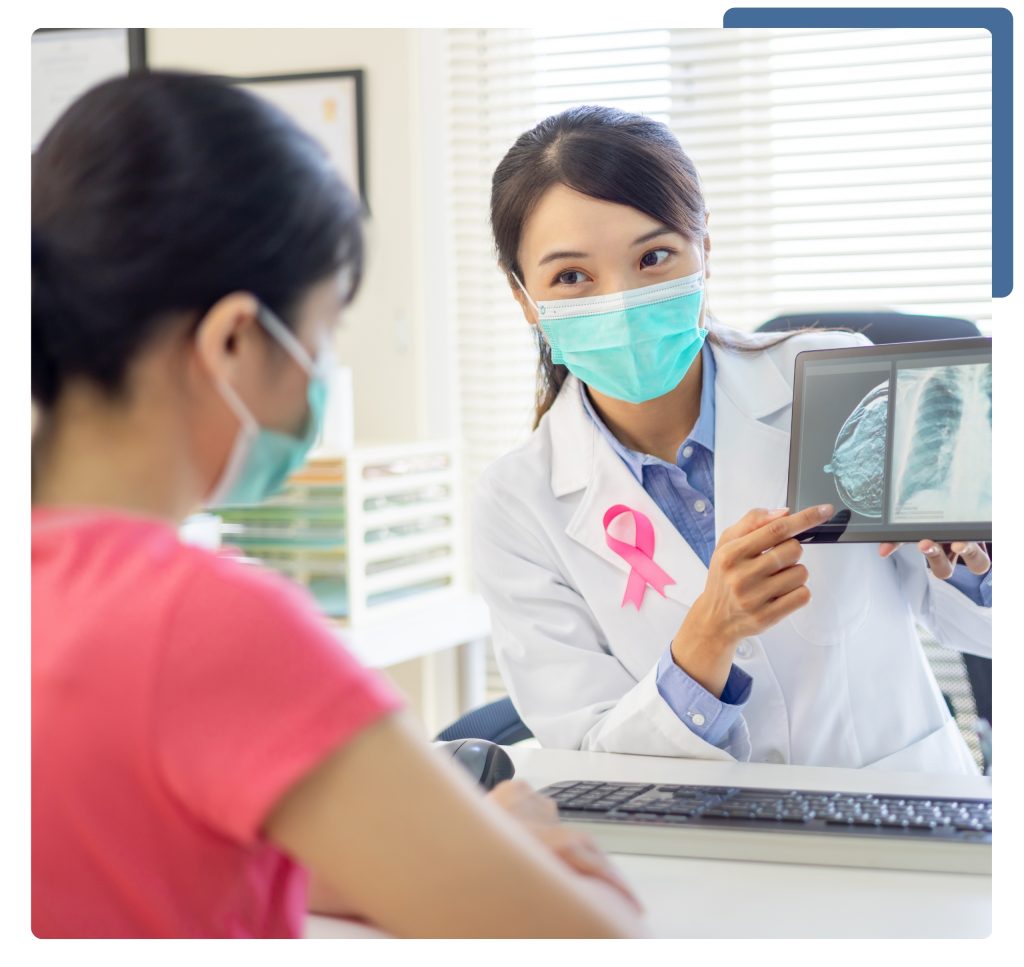 A woman wearing a mask and a doctor examining a tablet together in a clinical setting.